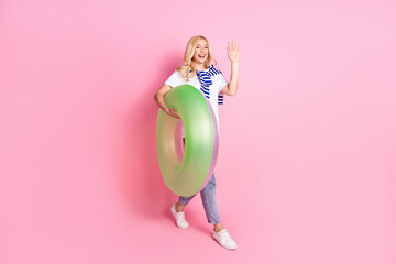Full size photo of pretty young female inflatable ring walk wave hand hi wear trendy white outfit isolated on pink color background