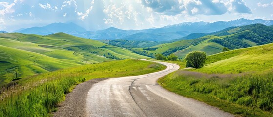 Obraz premium Serene winding road through lush green hills under a bright sky, perfect for nature lovers and travel enthusiasts.