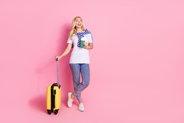 Full size photo of pretty young female suitcase hold tickets look empty space wear trendy white outfit isolated on pink color background