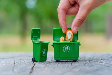 Hand Placing Food Waste Into Mini Green Bin For Disposal