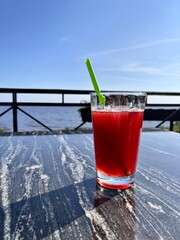 A glass of mors on a black marble table in the restaurant summer terrace on a sea backdrop .Food background