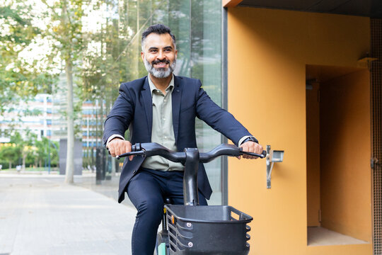 Smiling Indian businessman riding an electric bike in the city
