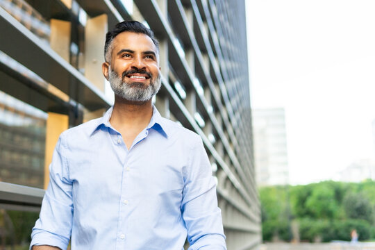 Smiling Indian businessman looking away in the city