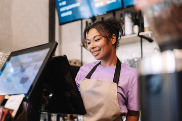 Young, smiling African American barista taking order on digital cash register