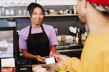 Smiling barista accepting credit card payment from customer