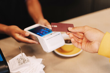Customer making a contactless payment using a credit card in a cafe selective focus