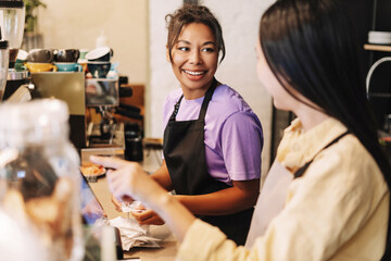 Two young baristas working together behind the counter in a coffee shop