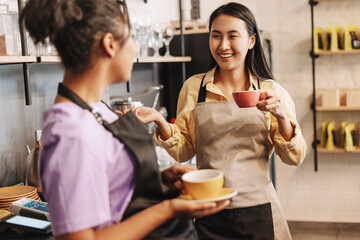 Two young baristas taking a break and chatting in their coffee shop