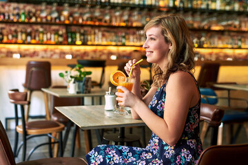 Woman, thinking and smile with cocktail for vacation, break and fun with drink. Happy hour, holiday and girl in restaurant, club or bar with alcohol beverage for travel celebration or birthday