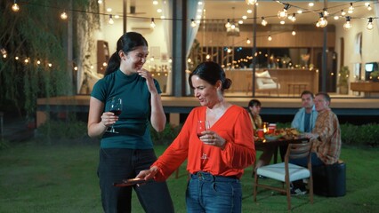 Family gather celebrate holiday. Focus Mother and grandmother drink wine and grill food for family member in dinner party. Outdoor activity spend time with relative cross generation gap. Divergence.