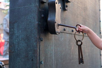 a small child's hand tries to open a padlock with a large key,