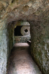 Large round capstone in a cave, part of the Way of the Cross along the road to the Madonna della Corona sanctuary near the village of Spiazzi in the Italian Alps.