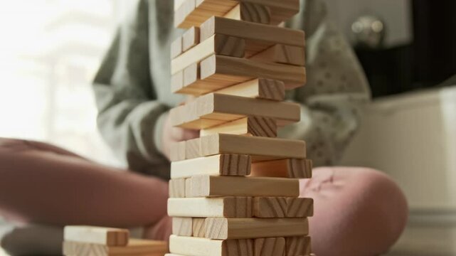 Little child plays a board game, kid builds from wooden bricks blocks. Children's educational games concept.