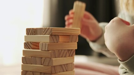 Little child plays a board game, kid builds from wooden bricks blocks. Children's educational games concept.