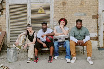 Portrait of multiracial friend band sitting on old bench and posing for photo