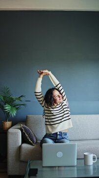 Freelancer taking a break from her laptop, stretching to relieve tension and refresh her energy while working from home. Freelancer woman stretching while working from home