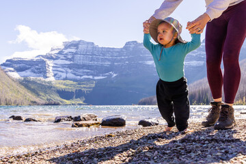 Mother Helping Baby Walk by Scenic Mountain Lake Shore