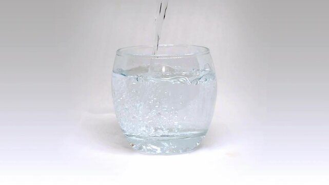  Pouring fresh cold fizzy mineral water into drinking glass on the table