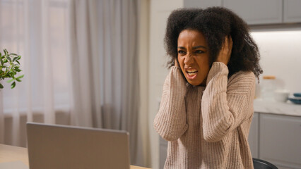 Annoyed angry woman African American businesswoman freelancer online working laptop at home kitchen...