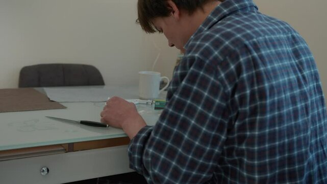 A young man prepares drugs on the table, back view