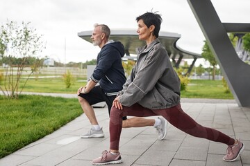 Side view of fit senior woman holding static lunge position strengthening leg muscles while working...