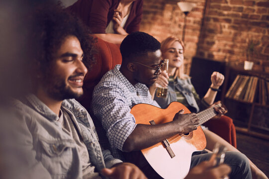 Friends hanging out playing guitar and having drinks