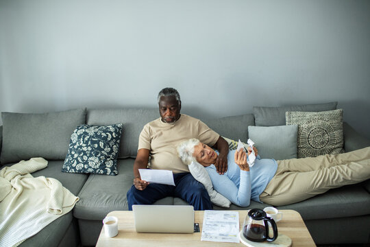 Diverse senior couple reading bills on the couch at home