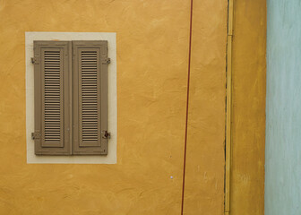 Ockerfarbene Hauswand mit Holzfenster verkörpert Mittelmeerromantik in zarten Farben und minimalistische Stille, niemand