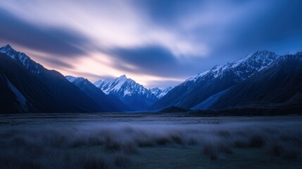 Snow-Capped Mountains at Twilight with Blurred Clouds and Grass in the Foreground