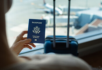 businesswoman holding US passport and luggage while standing at airport