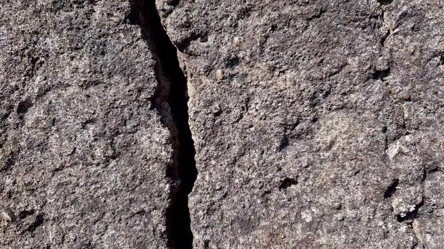 Crack in the stone. A crack, crevice in concrete stone, concrete surface. Authentic damaged concrete slab, crack in foundation,concrete top-down view