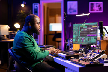 Creative songwriter recording new tracks with microphone and midi controller, playing piano notes in home studio. Skilled musician artist composing music with electronic keyboard and stereo gear.