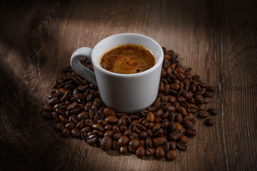 Fragrant hot coffee in a white cup with beans spilling roasted c