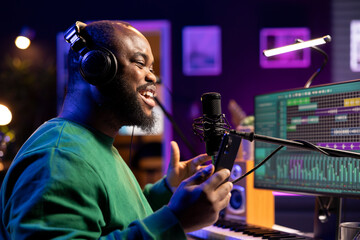 Young composer recording his new soundtrack on home studio microphone, performing his song before...