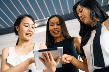 Three Asian women friends having conversation while looking at tablet computer in their hands. Concept of social media, gossip news and online shopping. uds