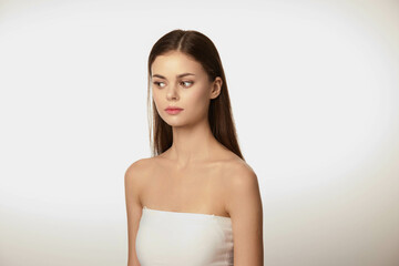 Young woman in strapless dress with serious expression, looking off to the side, isolated on white background