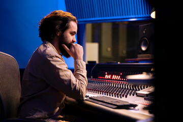 Sound engineer mixes individual tracks to create balanced music after audio recording session in...