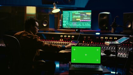 African american artist working with mockup on display in control room, mixing and mastering tracks...