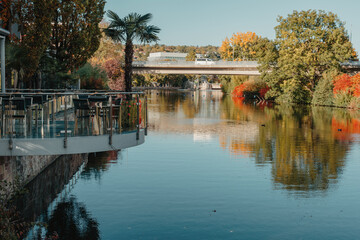 Obraz premium River On Sunset. Townhouses Buildings And Multi-floor Home At Waterfront. Sunset On River In City. Suburb Houses And Residential Building Near River In Europe. House In Nature On Shore On Sunset.