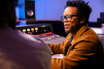 Audio technician and artist collaborating on music for pop rock album, processing and editing...