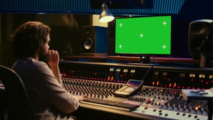 Sound designer watches online tutorials via greenscreen monitor to mix and master tracks and create...