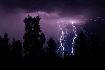 beautiful lightning during a thunderstorm at night in a forest that caused a fire, against a dark...