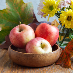 Apples in bowl, flowers and fall leaves, autumn season or Thanksgiving holiday concept, square