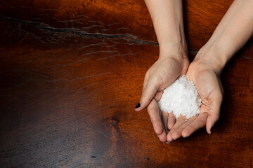 Manos con un puño de sal en una mesa de madera