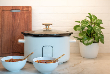 Slow cooker and soup bowls on a kitchen counter