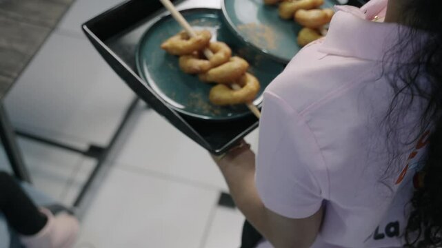 Waitress holding tray serving picarones peruvian dessert