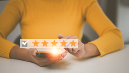 close up Woman hand using smart phone and give five star symbol to increase rating of product and...