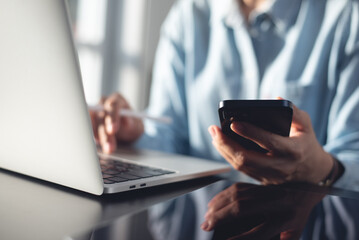 Business woman using mobile smart phone online working on laptop computer and tablet on table, surfing the internet, searching the information at office. student online studying from home, e-learning