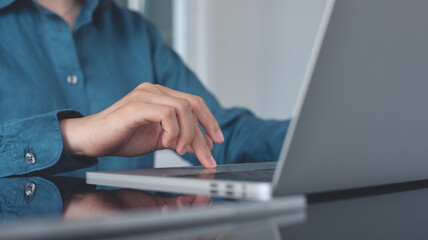 Close up, business woman working on laptop computer,  searching the information, surfing the internet with digital tablet on table. Woman hands typing on laptop, online working