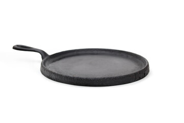 Vintage cast iron griddle. Round low frying pan with rim made of cast iron. Seasoned pan used to cook evenly on stove top and oven save. Vintage black cookware. White background. Selective focus.